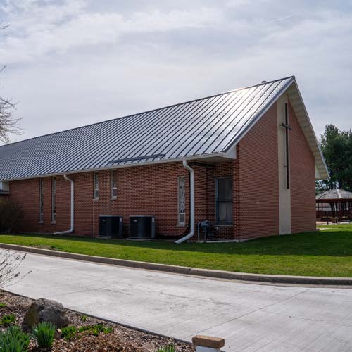 Brick church building with steep gray standing seam metal roof